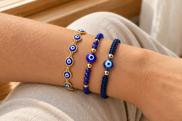 Three blue and gold evil eye bracelets worn together on a wrist