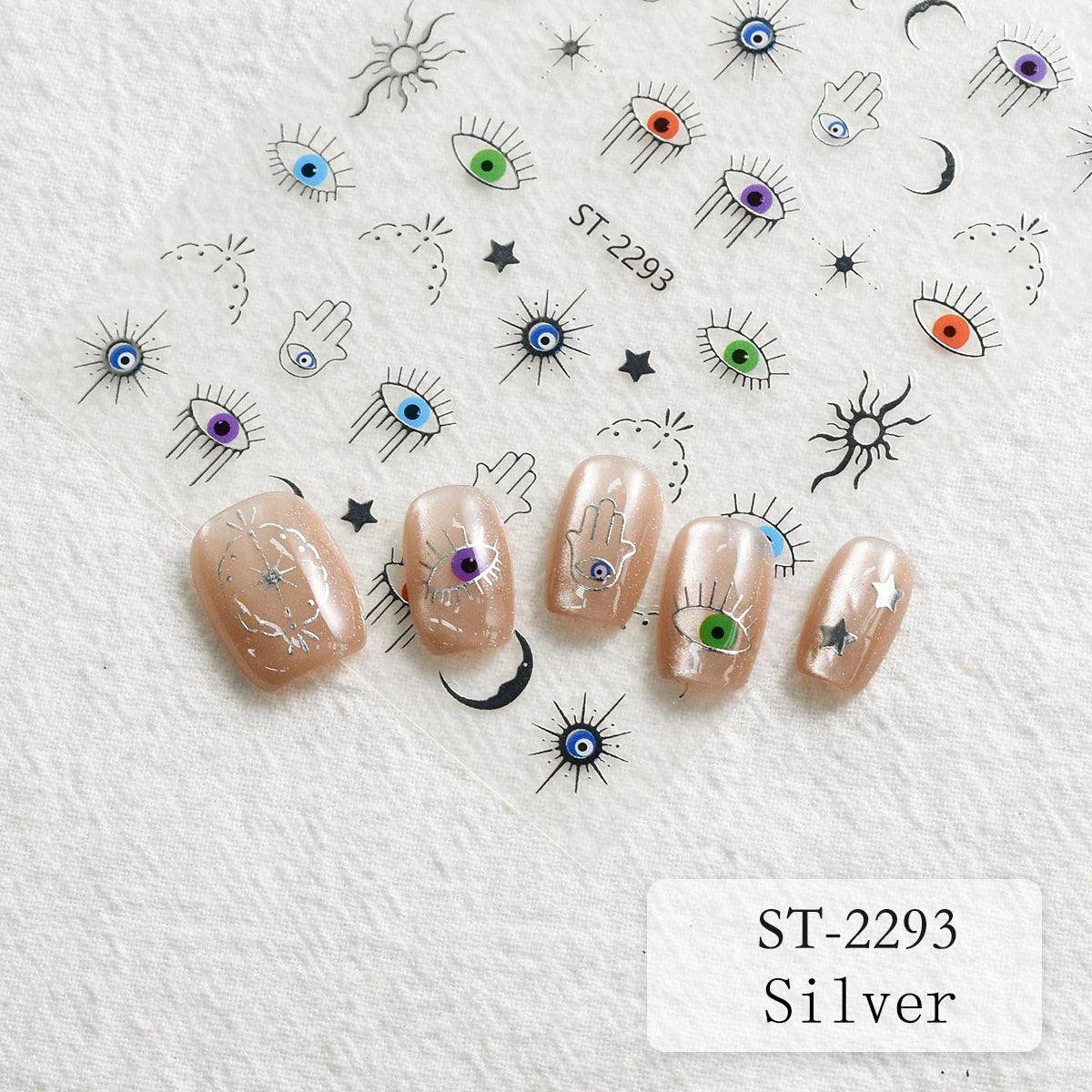 Five false nails displayed on a textured white background, decorated with silver glitter and small colorful evil eye and star motifs. Matching nail designs are also shown on a sheet above, with the text 'ST-2293 Silver' in the bottom right corner.