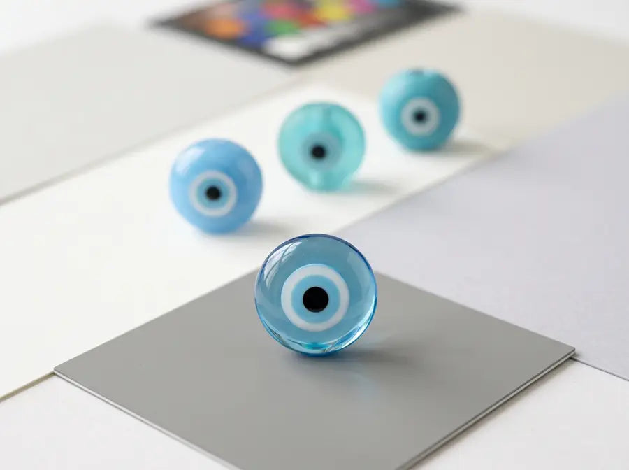 A sharp light-blue glass Nazar bead leads sky-blue, aqua, and turquoise examples with glossy, translucent, and matte finishes