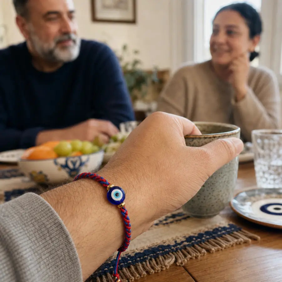 Sharp foreground wrist with red and blue protective bracelet while blurred people look on from a warm family table