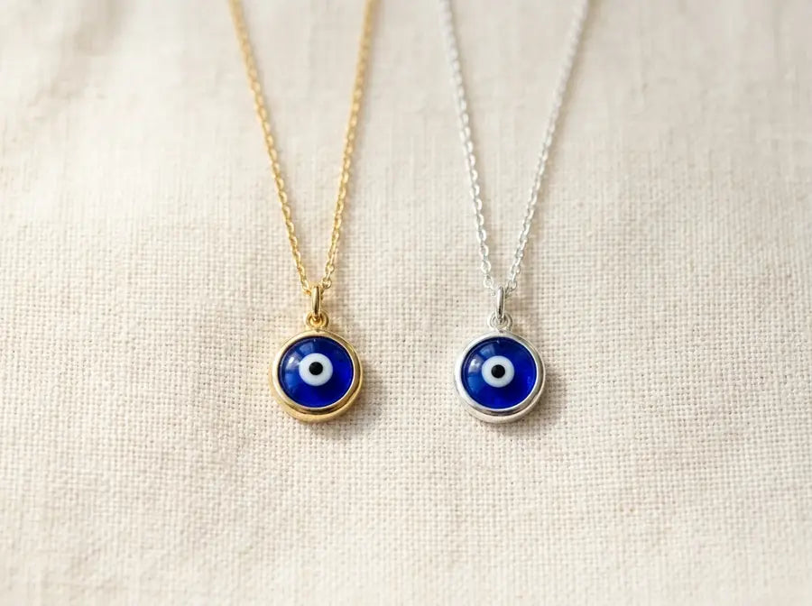 Gold piece and silver piece side by side both carrying the same blue evil eye as a shared connector