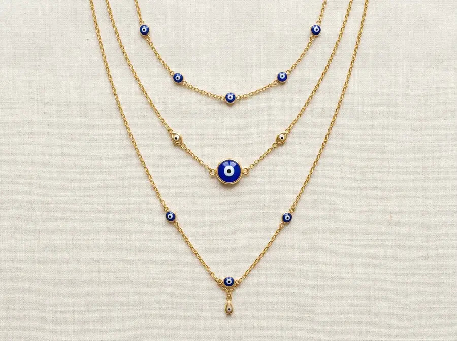 Three gold evil eye chains stepped in descending tiers with equal visible gaps between choker, focal, and lower lengths