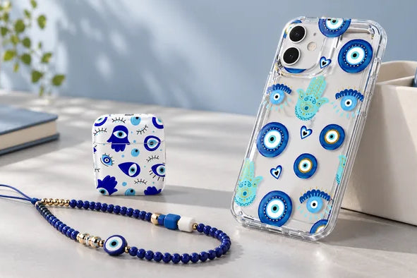 Blue evil eye phone case, earbud case and beaded phone strap on a light desktop