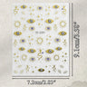 A sheet of decorative stickers featuring gold-toned suns, stars, evil eye motifs, and snake illustrations on a white background, with printed dimensions showing 9.1 cm by 7.
