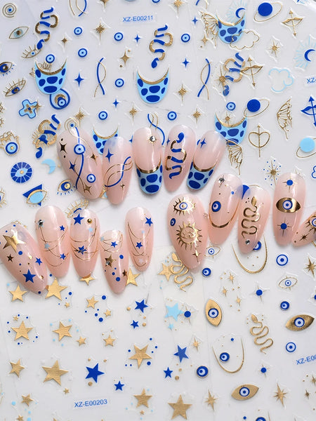 Blue and gold-tone 3D evil eye nail stickers shown across six manicure designs