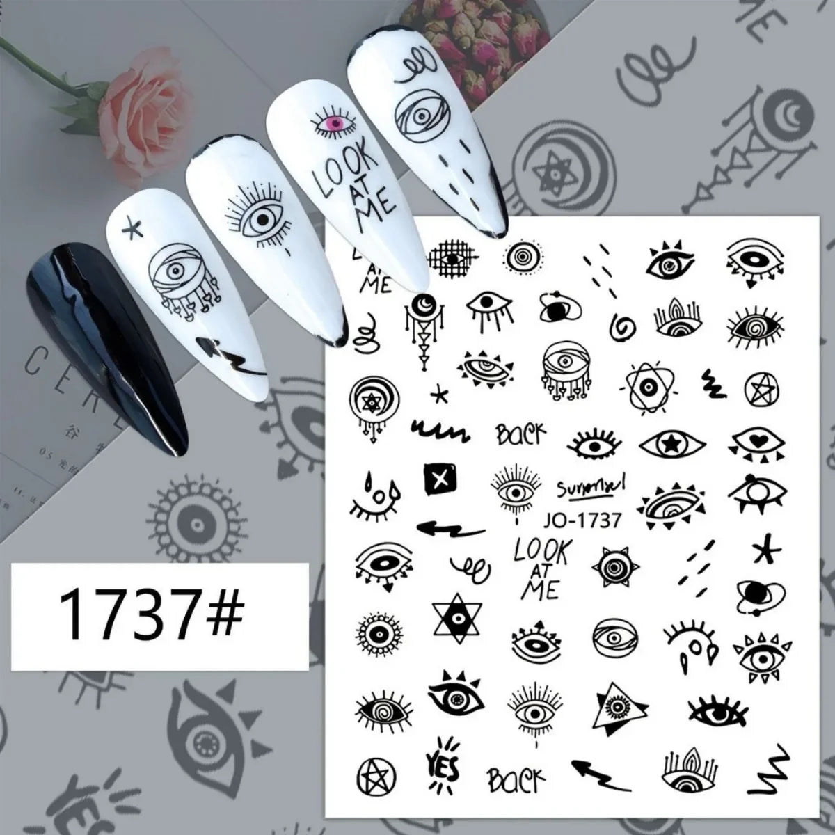 Black line-art eye and symbol nail stickers displayed on white manicure samples