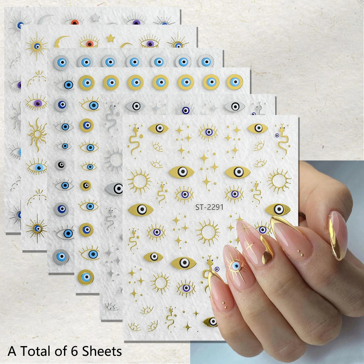 Six sheets of nail art stickers featuring gold and blue evil eye designs, shown with a hand displaying manicured nails decorated with matching stickers.