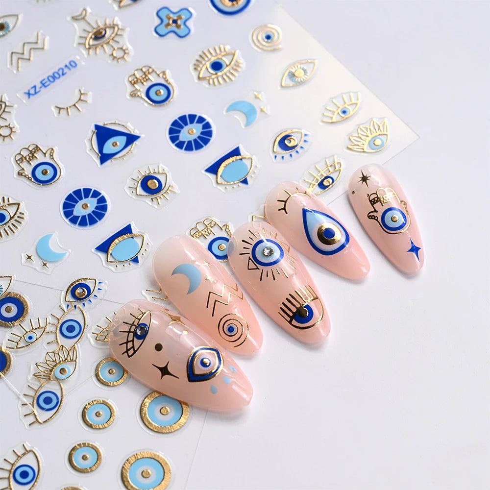 Blue and gold-tone evil eye nail stickers beside a manicure with eye, Hamsa, moon, and star motifs