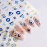 Blue and gold-tone evil eye nail stickers beside a manicure with eye, Hamsa, moon, and star motifs