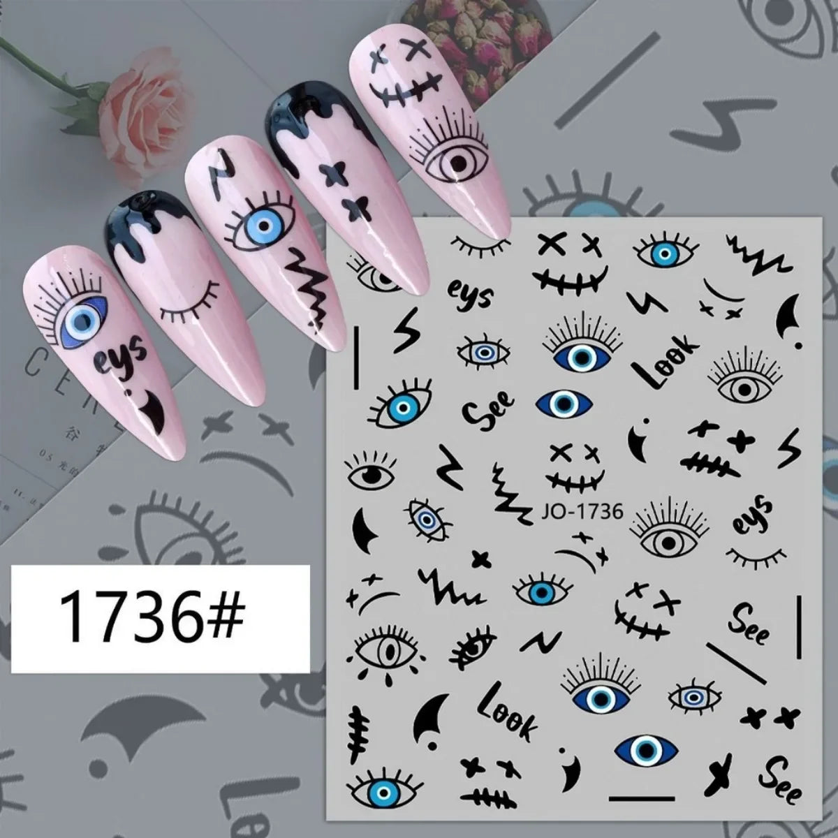 Black and blue graphic eye nail stickers displayed on pink manicure samples