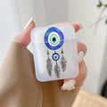Frosted earphone case with blue circular eye artwork and three illustrated black feathers, held in one hand.