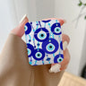 Handheld earphone case with illustrated blue circular eye charms hanging among turquoise and blue bead strands.