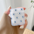 Handheld frosted earphone case with repeating small blue eyes outlined in black with fine lashes.