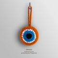 Front view of the Orange evil eye charm with an orange border and loop surrounding white and turquoise blue rings and a black center.