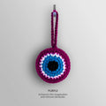 Front view of the Purple evil eye charm with a purple border and loop surrounding white and turquoise blue rings and a black center.