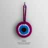 Front view of the Purple evil eye charm with a purple border and loop surrounding white and turquoise blue rings and a black center.