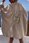 Back view of a beige shirt with a sequin eye motif, crinkled texture and a folded collar
