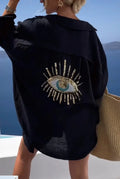 Back view of a black shirt with a turquoise eye motif and gold tone sequin details