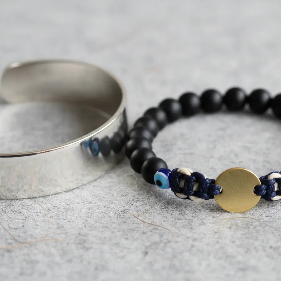 Close-up of polished metal, matte beads, and woven cord bracelet textures