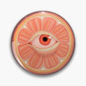 Round orange and pink citrus-slice button pin with a red eye at its center.