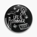 Black round button pin with Life Is Strange lettering, a triangular eye, bird, butterflies and cassette in white.
