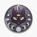 Round dark button pin with a three-eyed black cat, purple illustrated crystals, stars and moon phases.