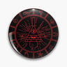Black round button pin with red line art of a triangular eye character wearing a top hat, surrounded by symbols.