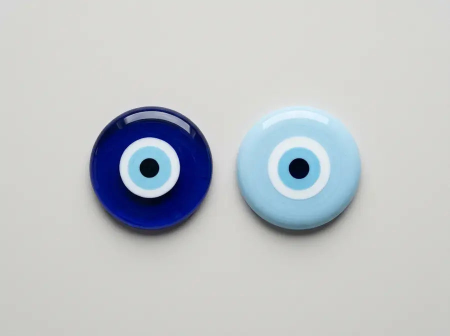 Equal-size dark cobalt and pale blue Nazar beads share identical eye patterns, lighting, spacing, and viewing angle.