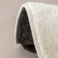 Folded white mat showing its bound edge and black backing covered in pale dots