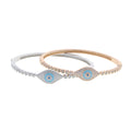 Silver tone and rose gold tone evil eye bangles overlapping on a white background