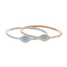 Silver tone and rose gold tone evil eye bangles overlapping on a white background