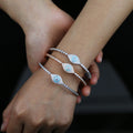 Silver tone and rose gold tone evil eye bangles stacked on one wrist