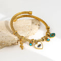 Gold tone bangle angled to show the snake, heart eye and turquoise-colored eye charms