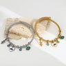 Gold tone and silver tone evil eye bangles side by side with snake and heart charms