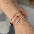 Pink, red and blue evil eye bangles shown together on a wrist
