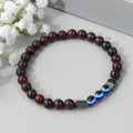 Red and black beaded bracelet with three blue eye beads, viewed from above