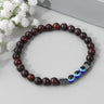 Red and black beaded bracelet with three blue eye beads, viewed from above