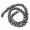 Black flat round beads with white and pale blue eye rings, arranged in a loop