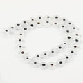 Clear flat round beads with white eye rings and dark centers, arranged in a loop