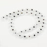 Clear flat round beads with white eye rings and dark centers, arranged in a loop