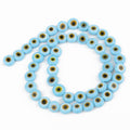 Light blue flat round beads with yellow eye rings and dark centers on a looped strand
