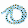 Light blue flat round beads with yellow eye rings and dark centers on a looped strand