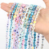 Pastel and blue iridescent evil eye bead strands draped over an open hand