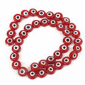 Red flat round beads with white eye rings and black centers on a looped strand