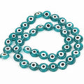 Teal flat round beads with white eye rings and black centers, arranged in a loop