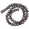 Very dark translucent beads with white eye rings and dark centers, arranged in a loop