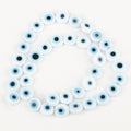 White flat round beads with light blue eye rings and black centers, arranged in a loop