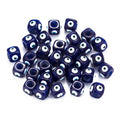 Scattered blue cube evil eye beads showing patterned faces and circular openings