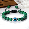 Green beads with dark stripes surrounding a blue eye, with silver tone accents and knotted black cord