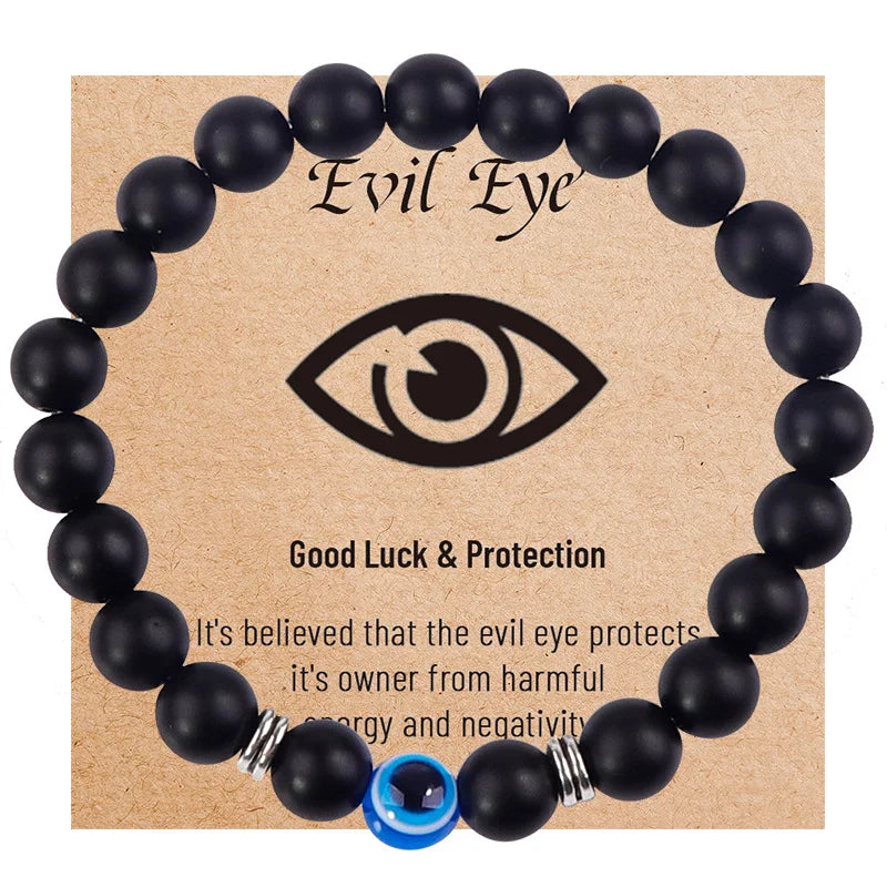 Matte black round bead bracelet with a blue eye bead and silver tone spacers on a printed card